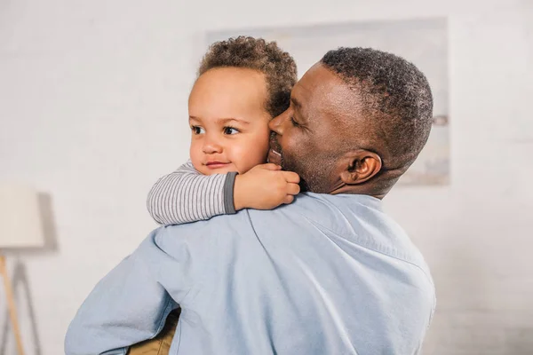 Happy African American Grandfather Hugging Adorable Little Grandson Home — стоковое фото