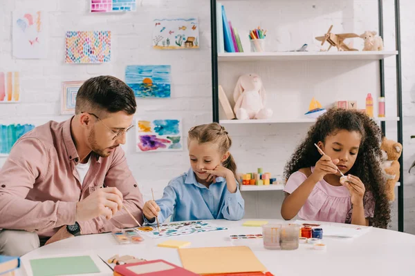 Teacher Eyeglasses Multiracial Children Drawing Pictures Paints Table Classroom — стоковое фото