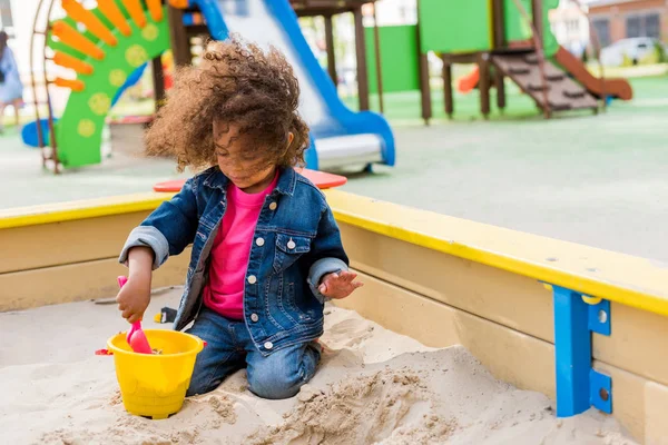 Curly African American Little Child Playing Plastic Scoop Bucket Sandbox — стоковое фото