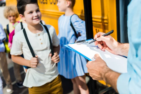 Cropped Shot Teacher Writing List Clipboard While Pupils Entering School — стоковое фото