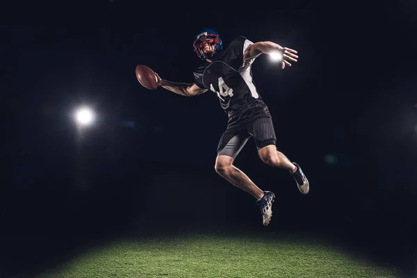 American Football Player Jumping Ball Spotlights Black — стоковое фото