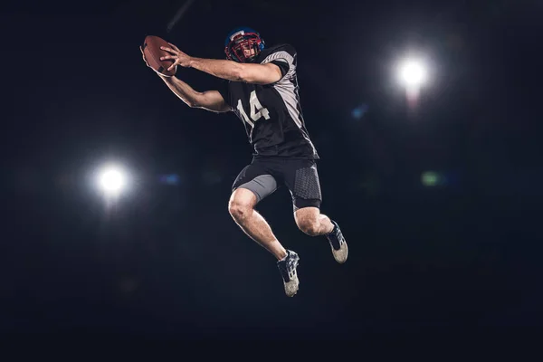 Bottom View American Football Player Jumping Ball Spotlights Black — стоковое фото