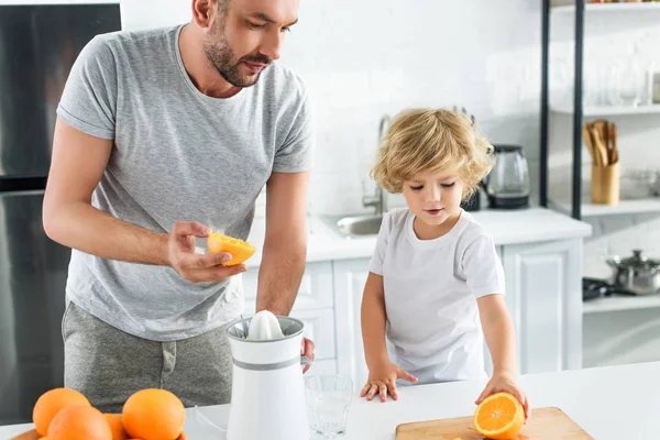 Little Boy Giving Father Orange Making Fresh Juice Kitchen — стоковое фото