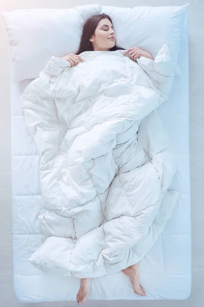 Молодой леди, спать в кровати с пуховым одеялом — стоковое фото
