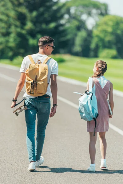 Back View Teenage Girl Boy Backpacks Books Skateboard Walking Talking — стоковое фото