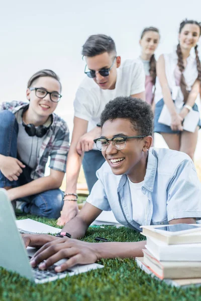 Happy Multiethnic Teenage Friends Using Laptop Studying Park — стоковое фото