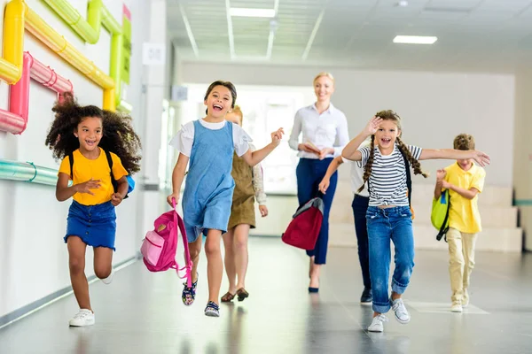 Adorable Happy Schoolchildren Running School Corridor Together Teacher Walking — стоковое фото