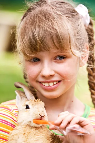 Счастливая девушка, кормить кролика с морковкой — стоковое фото