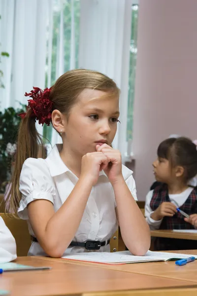 Грустная девушка сидит за столом школа — стоковое фото