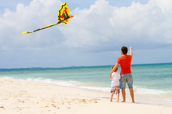 Отец и сын летающих змей на пляже — стоковое фото
