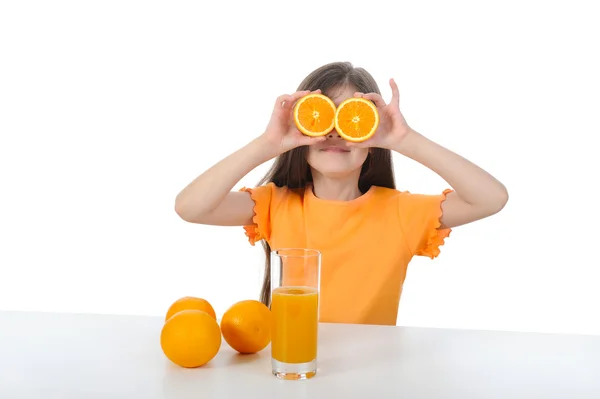 Девушка за столом с апельсинами и сок — стоковое фото