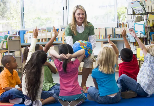 Воспитателя и детей с руки, поднятые в библиотеке — стоковое фото