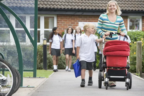 Женщина с коляски, ходьбе ее сына домой от школы — стоковое фото
