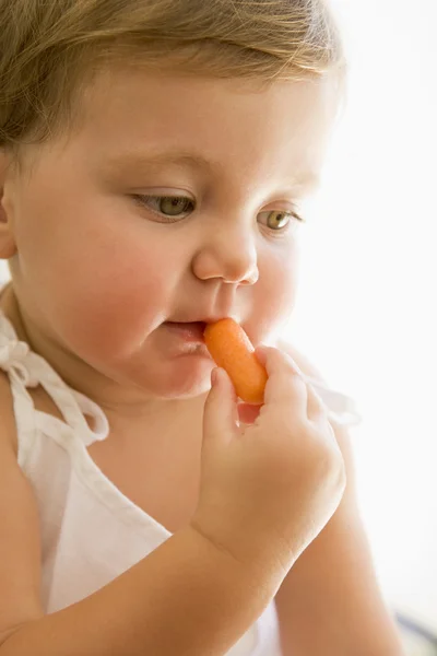 Ребенок в помещении ест морковь — стоковое фото