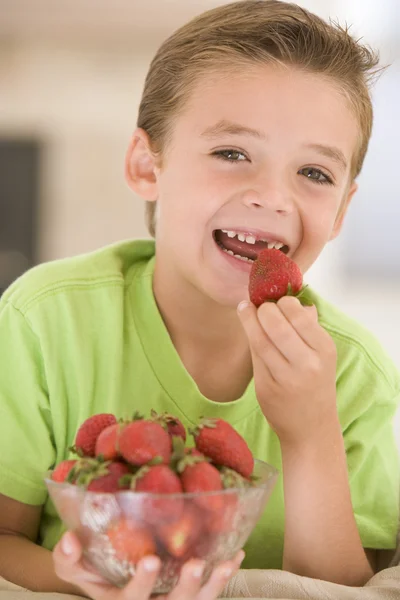 Молодой мальчик ест клубнику в гостиной улыбается — стоковое фото