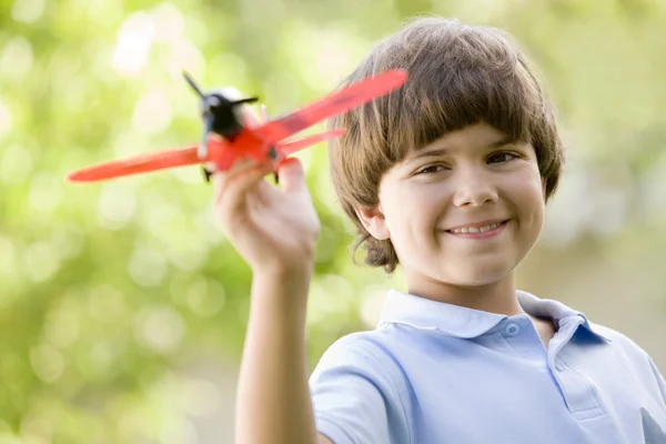 Мальчик с игрушка самолет на улице улыбается — стоковое фото