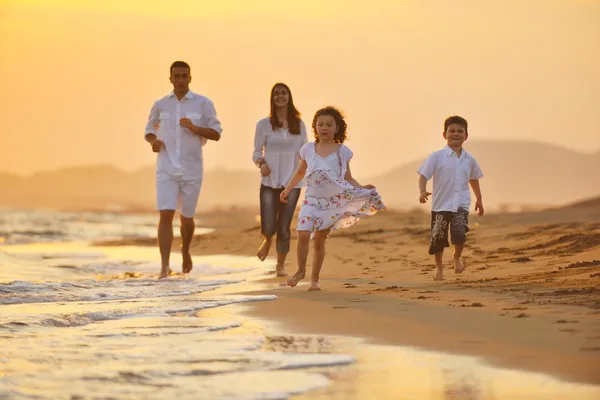 Счастливая молодая семья весело на пляже на закате — стоковое фото