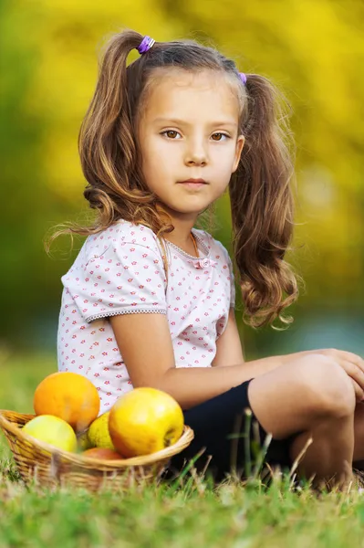 Ребенок сидит на траве с фруктами — стоковое фото