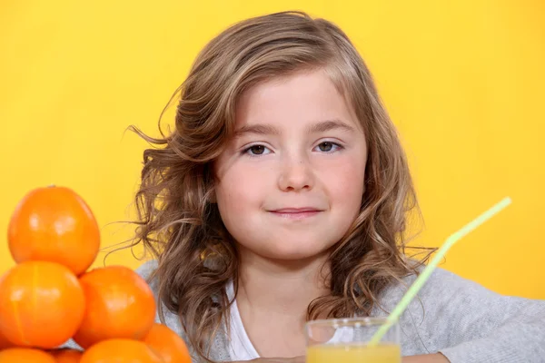 Молодая девушка с апельсинами и стакан сока — стоковое фото