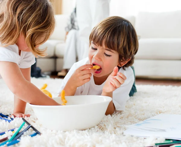 Симпатичные дети едят чипсы и рисование — стоковое фото