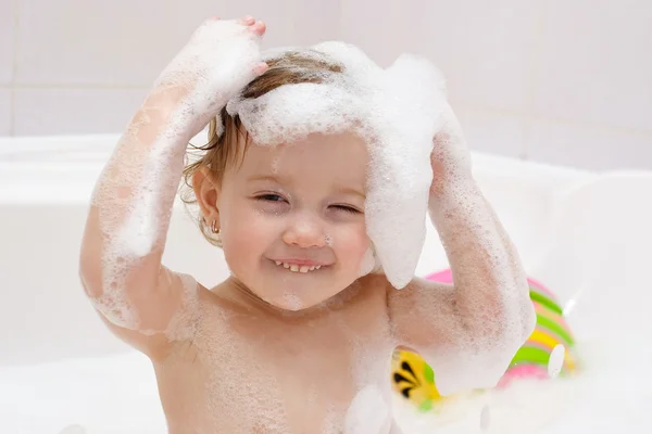 Маленький ребенок моет волосы в ванной — стоковое фото